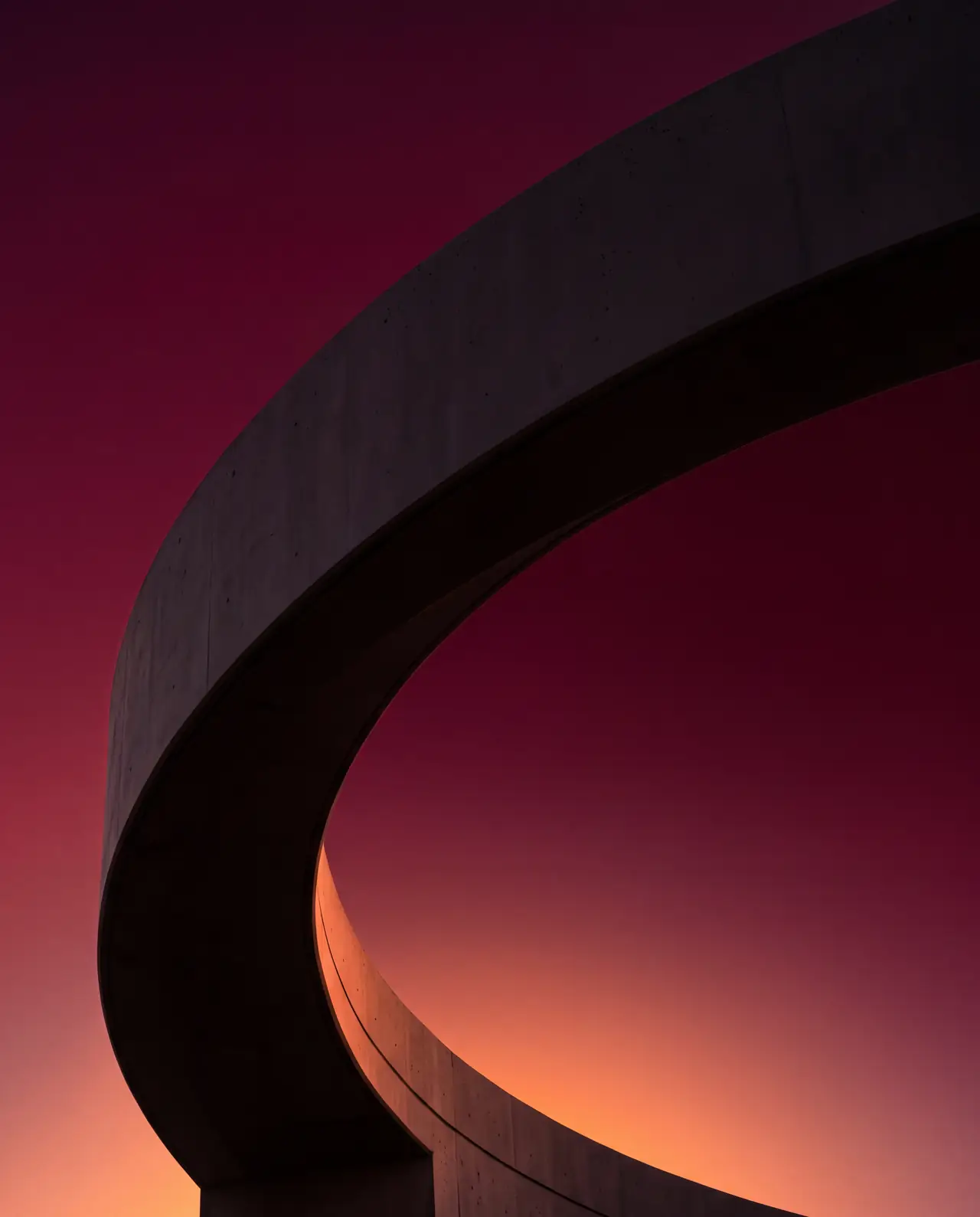 Abstract architectural fragment at coastal Florida twilight — a single curved wall lit from below by fading sunset light bleeding into deep burgundy sky.