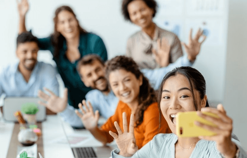 Diverse and cheerful team taking a selfie together in a modern office setting.